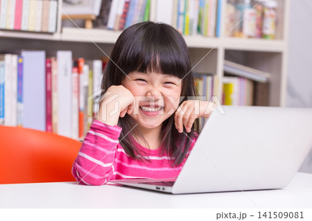 Joyful Asian Girl Student Typing on Laptop for Homework in Study Room Joyful Asian Girl Student Typing on Laptop for Homework in Study Room 141509081