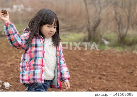 Little girl in a checkered jacket exploring a ploughed field and holding earth in spring. Little girl in a checkered jacket exploring a ploughed field and holding earth in spring. 141509099