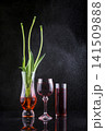 Still life with wine glasses against a dark background and branches of fallen flowers 141509888