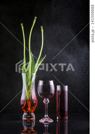 Still life with wine glasses against a dark background and branches of fallen flowers 141509888