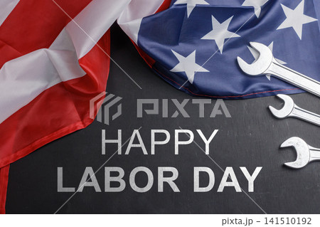 Happy Labor Day banner with American flag folds, chrome steel wrenches, and text on a dark wooden background. High Quality Photo Happy Labor Day banner with American flag folds, chrome steel wrenches, and text on a dark wooden background. High Quality Photo 141510192