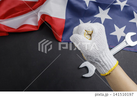 Raised gloved fist with wrench and American flag on dark background for Labor Day. High Quality Photo Raised gloved fist with wrench and American flag on dark background for Labor Day. High Quality Photo 141510197