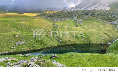 A sheep flock grazes above Green Abudelauri Lake as snowmelt streams cross alpine pasture in Georgia A sheep flock grazes above Green Abudelauri Lake as snowmelt streams cross alpine pasture in Georgia 141511053