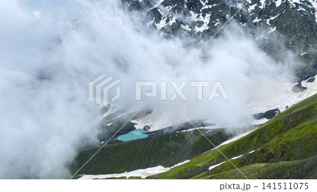 White Abudelauri Lake appears through mountain clouds below Chaukhi Pass in Georgia White Abudelauri Lake appears through mountain clouds below Chaukhi Pass in Georgia 141511075