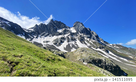 Chaukhi Mountain rises above the alpine pass in Georgia with jagged rock towers, snowfields, and grassy slopes Chaukhi Mountain rises above the alpine pass in Georgia with jagged rock towers, snowfields, and grassy slopes 141511095