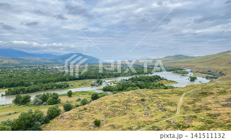 Kura River branches across a valley below Uplistsikhe in an elevated panoramic shot, linking wooded floodplains Kura River branches across a valley below Uplistsikhe in an elevated panoramic shot, linking wooded floodplains 141511132