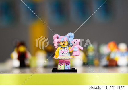 A toy minifigure of a girl with pink and blue ponytails holding a teddy bear. A toy minifigure of a girl with pink and blue ponytails holding a teddy bear. 141511185