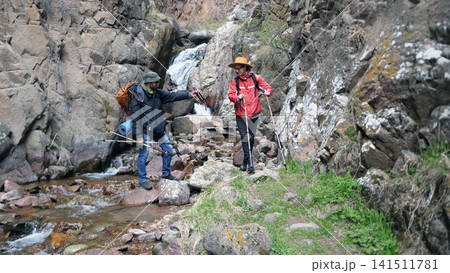 Two gay men are traveling in the mountains. A couple of friends are actively spending the weekend, they drink beer and enjoy the beauty of nature Two gay men are traveling in the mountains. A couple of friends are actively spending the weekend, they drink beer and enjoy the beauty of nature 141511781