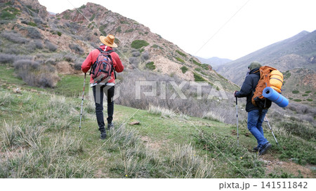 Two climbers climb the mountain, exploring a new route. A couple of friends are walking in the mountains. The guys travel together Two climbers climb the mountain, exploring a new route. A couple of friends are walking in the mountains. The guys travel together 141511842