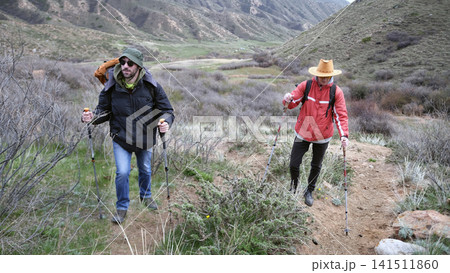 Two friends set off on a journey to a mountain peak. A trip in the mountains. Weekend camping trip. Trekking through hills 141511860