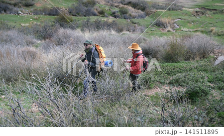 A couple of good friends are wandering in the thickets of dry bushes. Tourists travel to wild places. Two people are walking A couple of good friends are wandering in the thickets of dry bushes. Tourists travel to wild places. Two people are walking 141511895