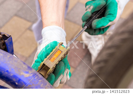 Man examining bike chain and gears for wear. Upside down position reveals issues. Practical competence outside house Man examining bike chain and gears for wear. Upside down position reveals issues. Practical competence outside house 141512023