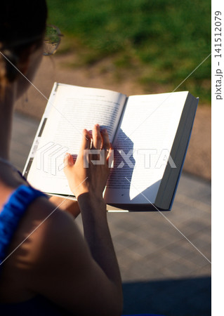 Girl sitting on grass with book. Summer reading ritual. Screen free zone. Intellectual growth through literature. Peaceful harmony between human and nature 141512079