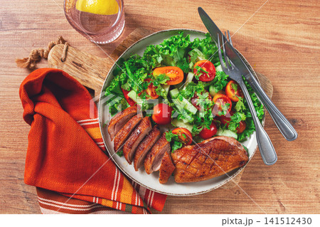 Delicious grilled duck breast served with fresh garden salad and cherry tomatoes at a rustic dining table Delicious grilled duck breast served with fresh garden salad and cherry tomatoes at a rustic dining table 141512430