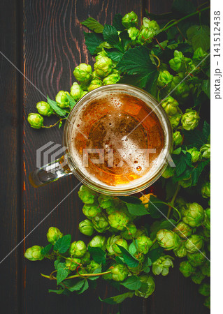 A mug of beer , on a wooden table, with a branch of fresh hops, rustic , no people, A mug of beer , on a wooden table, with a branch of fresh hops, rustic , no people, 141512438
