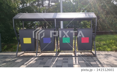 Four recycling bins with colored labels under metal shelter outdoors 141512601