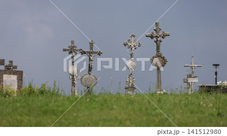 A tranquil view of an old cemetery with a row of ornate metal religious crosses and crucifixes A tranquil view of an old cemetery with a row of ornate metal religious crosses and crucifixes 141512980
