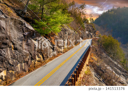 Scenic journey through Highlands Road in North Carolina. Rocky mountain sides and fall forest canopy create a stunning autumn drive. Scenic journey through Highlands Road in North Carolina. Rocky mountain sides and fall forest canopy create a stunning autumn drive. 141513376
