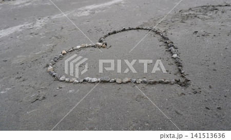 Close-up of a heart shape drawn in small pebbles on a textured gray concrete surface, roughness concept. Close-up of a heart shape drawn in small pebbles on a textured gray concrete surface, roughness concept. 141513636