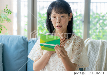 通帳を見てショックを受けるシニア女性 141516531