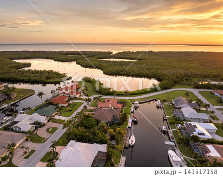 Wealthy waterfront neighborhood in southern Florida at sunset. Expensive houses surrounded by palm trees and reflecting evening glow. 141517158