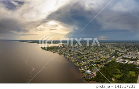 Tropical thunderstorm over Charlotte Harbor with dramatic dark clouds and rainfall pouring on Florida coastal town. Tropical thunderstorm over Charlotte Harbor with dramatic dark clouds and rainfall pouring on Florida coastal town. 141517233