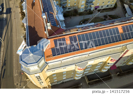 Top view of blue solar photo voltaic panels system on high apartment building roof top on sunny day. Renewable ecological green energy production concept. Top view of blue solar photo voltaic panels system on high apartment building roof top on sunny day. Renewable ecological green energy production concept. 141517256