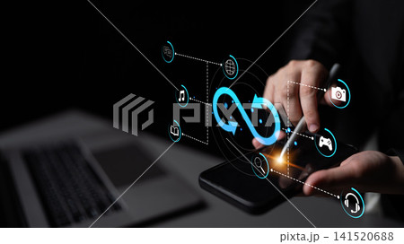 Hands using modern smartphone with futuristic technology interface and digital icons for connectivity and interaction in dark environment. Sentient Hands using modern smartphone with futuristic technology interface and digital icons for connectivity and interaction in dark environment. Sentient 141520688