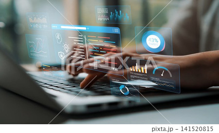 Hands typing on laptop with digital interface displaying graphs, charts, and analytical data in a modern workspace environment Gluon 141520815