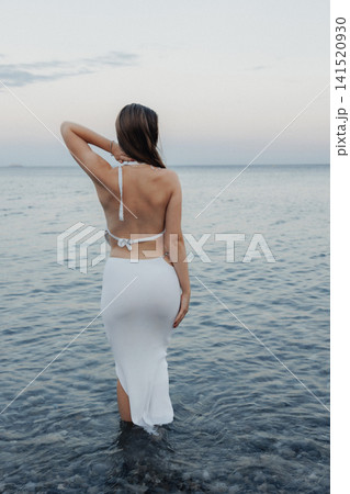 Woman stands knee-deep in calm ocean waters Woman stands knee-deep in calm ocean waters 141520930
