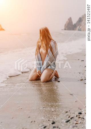 Woman beach sunset young woman kneeling on the sandy shore during sunset with gentle ocean waves Woman beach sunset young woman kneeling on the sandy shore during sunset with gentle ocean waves 141521497