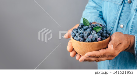 Hands Holding Wooden Bowl with Fresh Blueberries and Copy Space Hands Holding Wooden Bowl with Fresh Blueberries and Copy Space 141521952