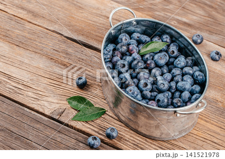Fresh Blueberries in Metal Bucket on Rustic Wooden Table Fresh Blueberries in Metal Bucket on Rustic Wooden Table 141521978