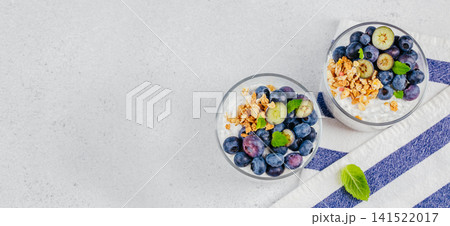 Blueberry yogurt parfait with granola in glass cups top view Blueberry yogurt parfait with granola in glass cups top view 141522017