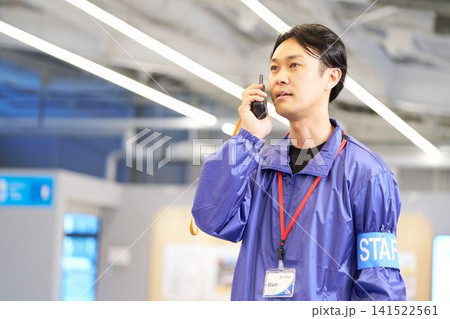 トランシーバーで連絡を取るイベントスタッフの男性 141522561