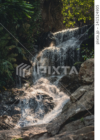 Waterfall flowing over rocks with splashing water in slow motion, natural stream cascade with rushing waters and textured stones, Huay Kaew, Chiang Mai, Thailand Waterfall flowing over rocks with splashing water in slow motion, natural stream cascade with rushing waters and textured stones, Huay Kaew, Chiang Mai, Thailand 141524905