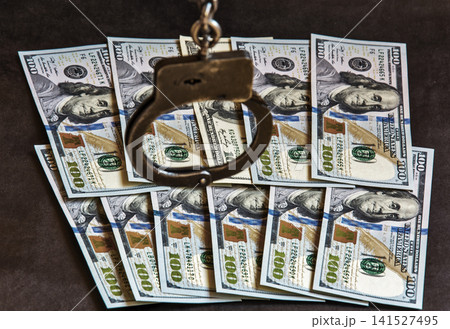 Handcuffs on one hundred banknotes of US dollars Handcuffs on one hundred banknotes of US dollars 141527495
