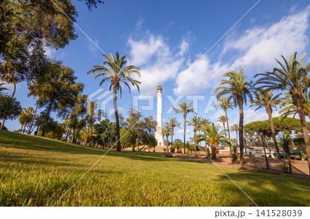 Historic Monument to the Discoverers at La Rabida Friary in Huelva, Andalusia, Spain. Sunny landmark surrounded by palm trees under a cloudy blue sky. 141528039