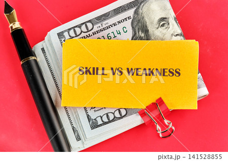 Business concept showing a yellow sign with text balanced against a stack of cash and a luxury fountain pen on a vibrant red background representing financial growth 141528855