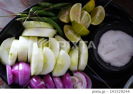 Fresh Indian meal accompaniment salad platter with sliced cucumbers onions green chillies lemons and salt Fresh Indian meal accompaniment salad platter with sliced cucumbers onions green chillies lemons and salt 141529244