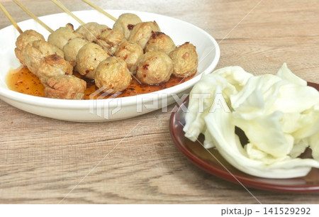 grilled beef tendon meatball stabbing in wooden stick dressing spicy and sweet tamarind sauce on plate with fresh cabbage salad grilled beef tendon meatball stabbing in wooden stick dressing spicy and sweet tamarind sauce on plate with fresh cabbage salad 141529292