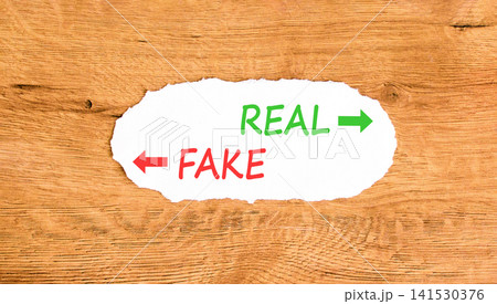 Real or fake words symbol. Concept words Fake and Real on beautiful white paper. Beautiful wooden background. Business and real or fake concept. Copy space. Real or fake words symbol. Concept words Fake and Real on beautiful white paper. Beautiful wooden background. Business and real or fake concept. Copy space. 141530376