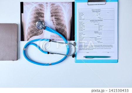 Stethoscope lies on a doctor's desk next to medical documents and a chest x-ray of a patient in a pulmonology department. Treatment of lung diseases Stethoscope lies on a doctor's desk next to medical documents and a chest x-ray of a patient in a pulmonology department. Treatment of lung diseases 141530433