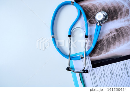 Stethoscope rests on medical report and x-ray at a clinic desk in hospital with space for text. Medical setting, top view 141530434