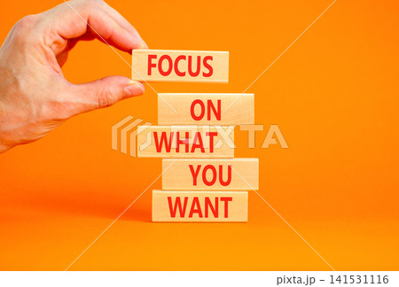 Focus on what you want symbol. Concept words Focus on what you want on beautiful wooden blocks. Beautiful orange background. Psychologist hand. Psychological focus on what you want concept. Copy space 141531116