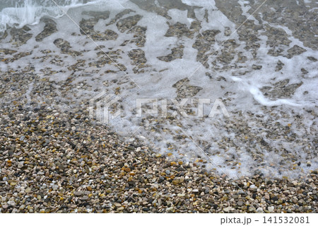 Pebble beach with sea foam background Pebble beach with sea foam background 141532081