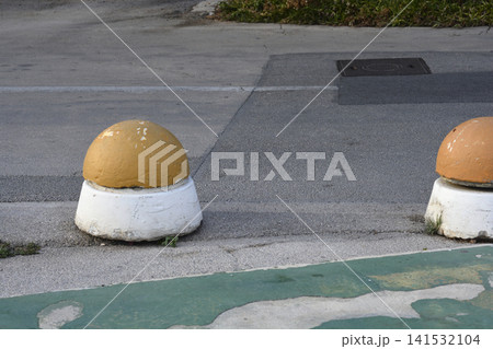 Concrete bollards on asphalt road edge 141532104