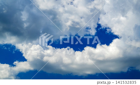 dark and white cumulus clouds with a clearance of blue sky in the center 141532835