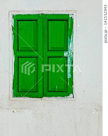Old green wooden window frame set against rustic white painted wall Closed vintage green wooden window on white weathered concrete wall. Old green wooden window frame set against rustic white painted wall Closed vintage green wooden window on white weathered concrete wall. 141532943