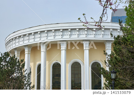 Neoclassical building with white columns and arch windows. Architecture landmark surrounded by garden trees. Urban travel destination and classic city government office exterior design. Neoclassical building with white columns and arch windows. Architecture landmark surrounded by garden trees. Urban travel destination and classic city government office exterior design. 141533079